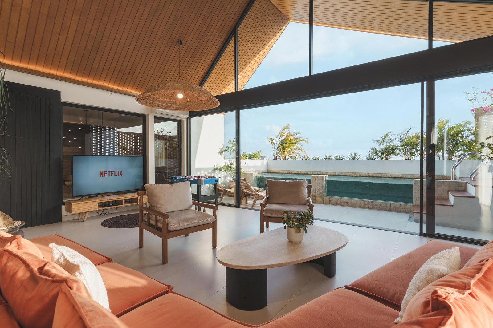 Rooftop living room with large TV and foosball table overlooking the pool