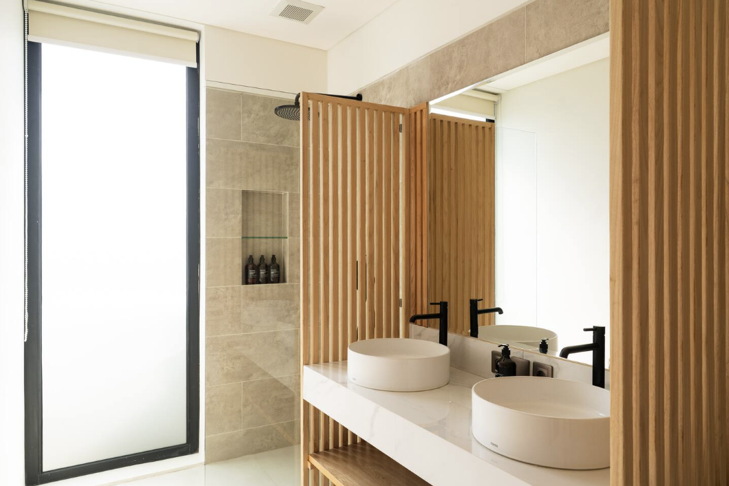 Bathroom with wood slat divider, double vessel sinks and walk-in shower