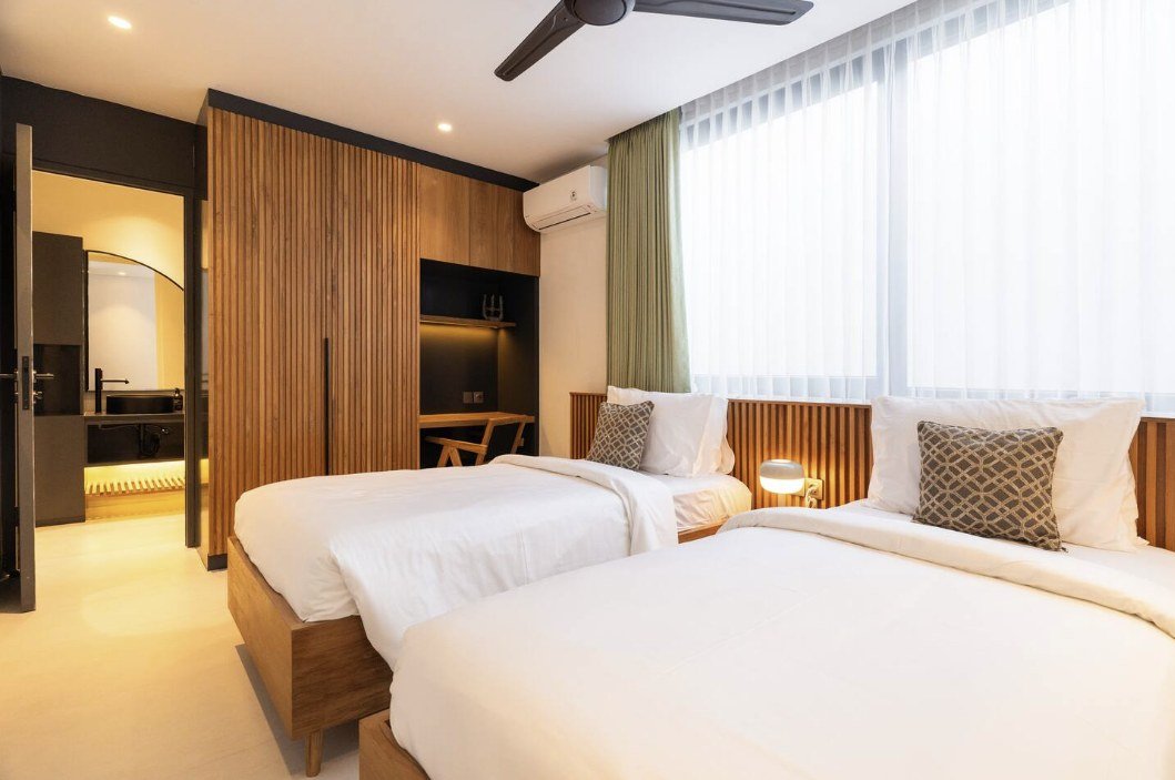 Twin bedroom with wood cabinetry and ensuite visible through open door