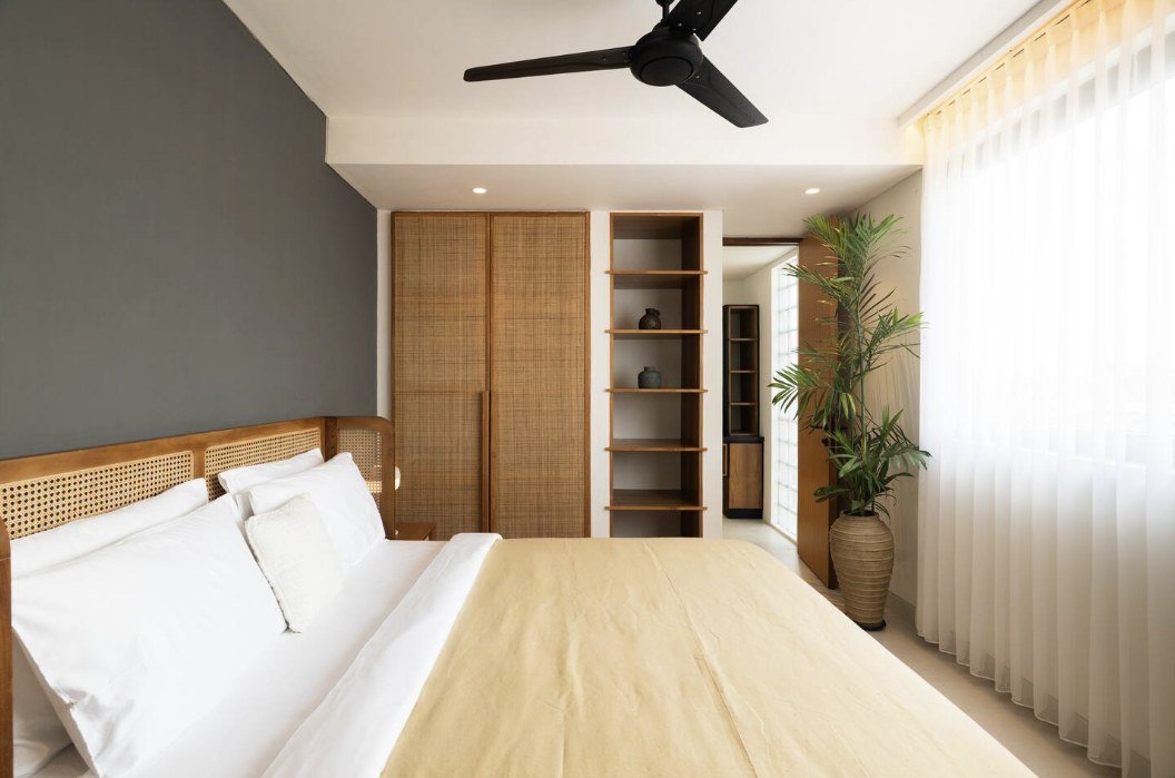 Bedroom with charcoal accent wall, rattan headboard and wardrobe